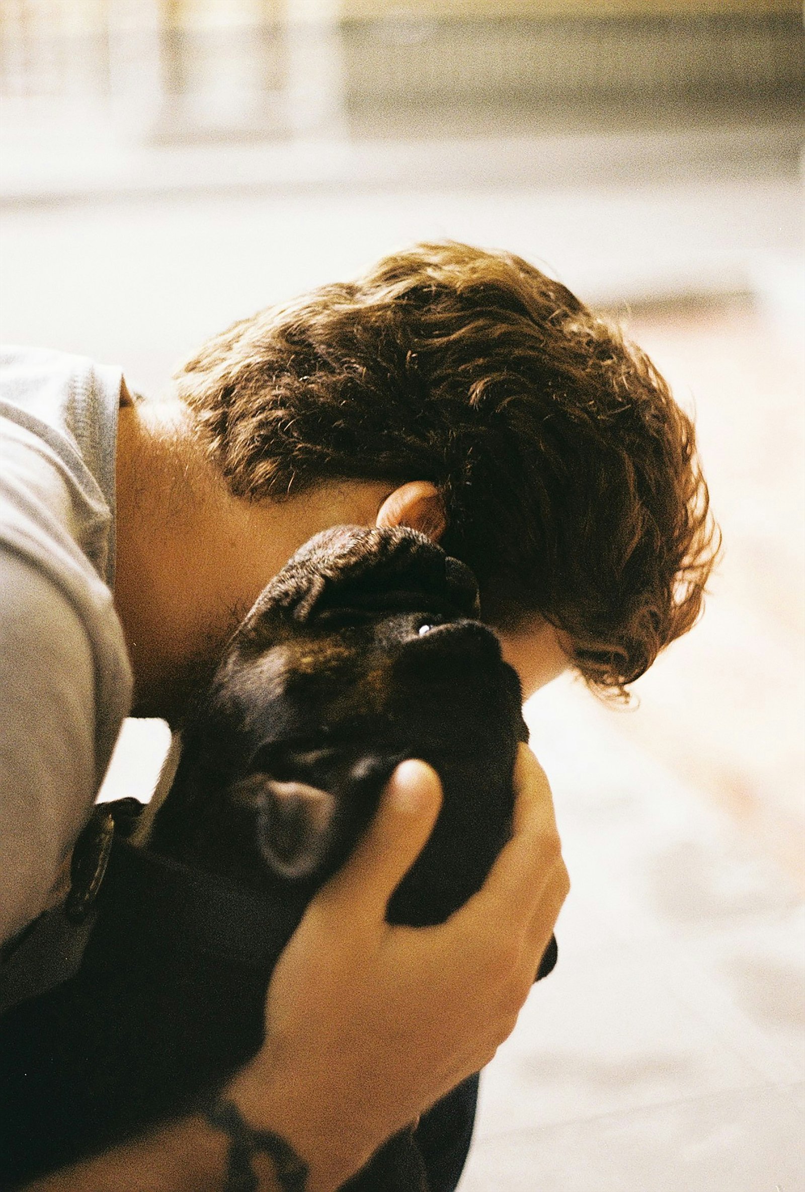 Homem a beijar um cachorro preto que segura nas mãos